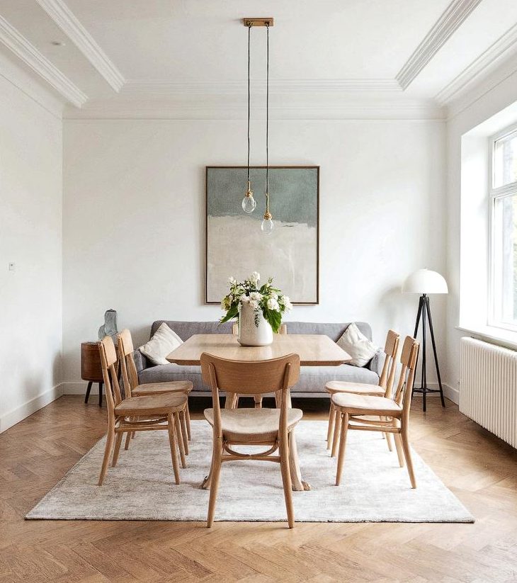Comedor moderno con mesa de madera, sillas, lámpara y un cuadro en la pared.